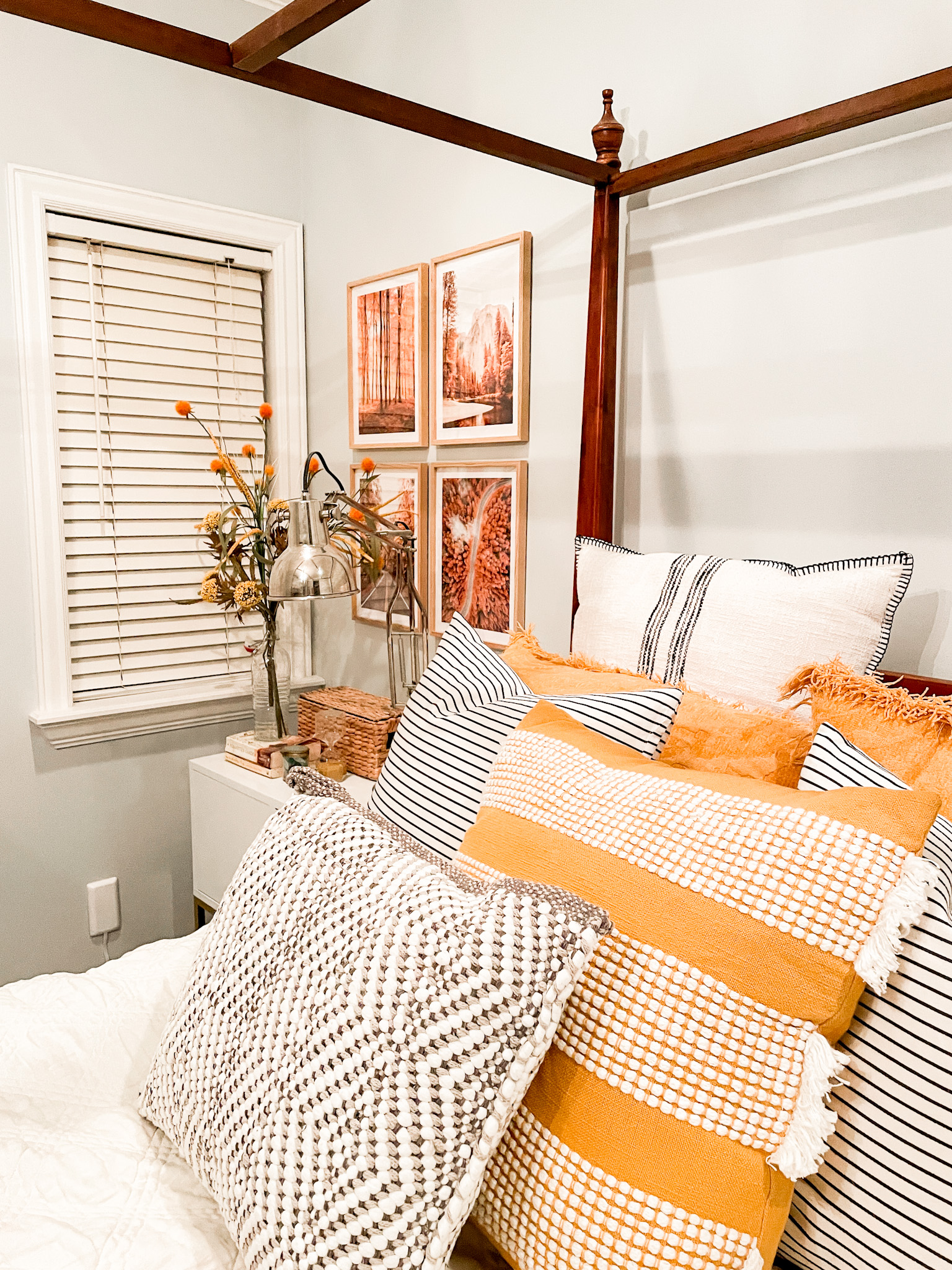 four fall prints in a bed room with bed and side table