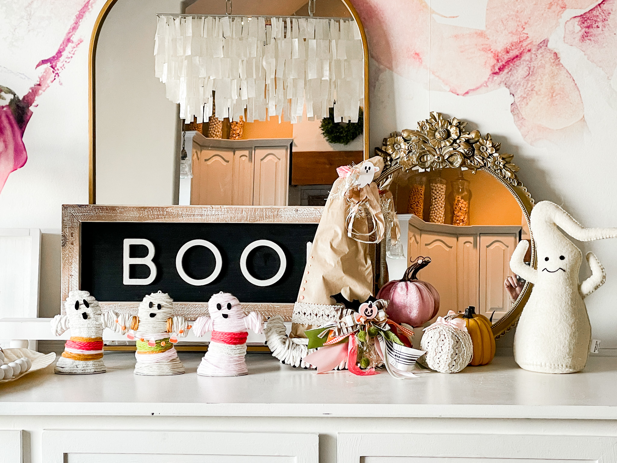 dinning room sideboard with halloween decor of paper witches hat, boho yarn ghost from the dollar store and two mirrors